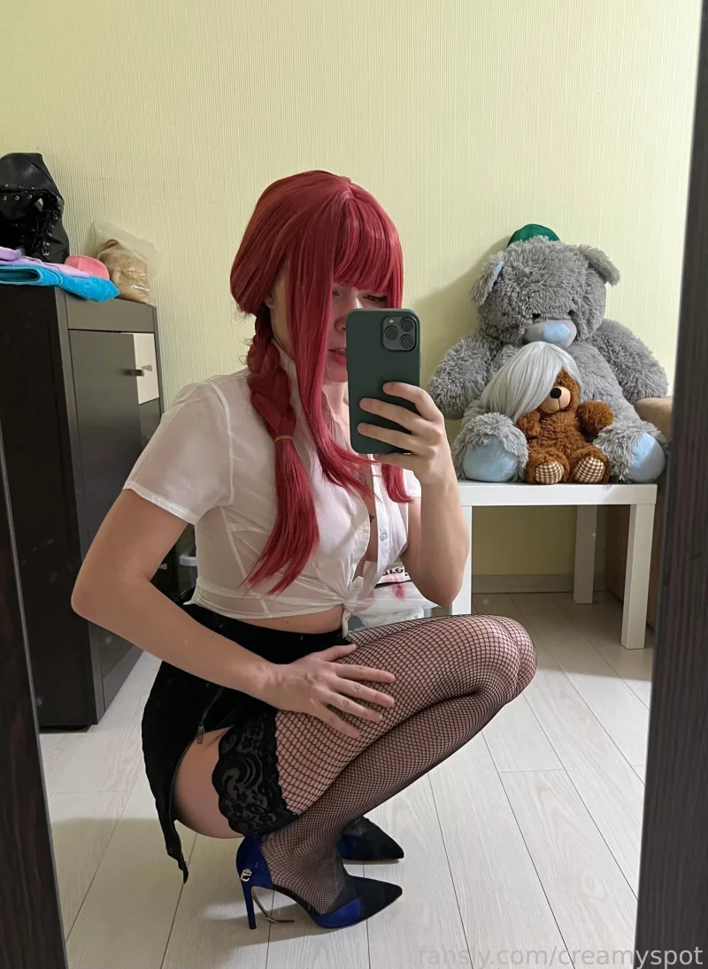 Naughty Creamy Spot squatting in fishnets and a white top, taking a mirror selfie