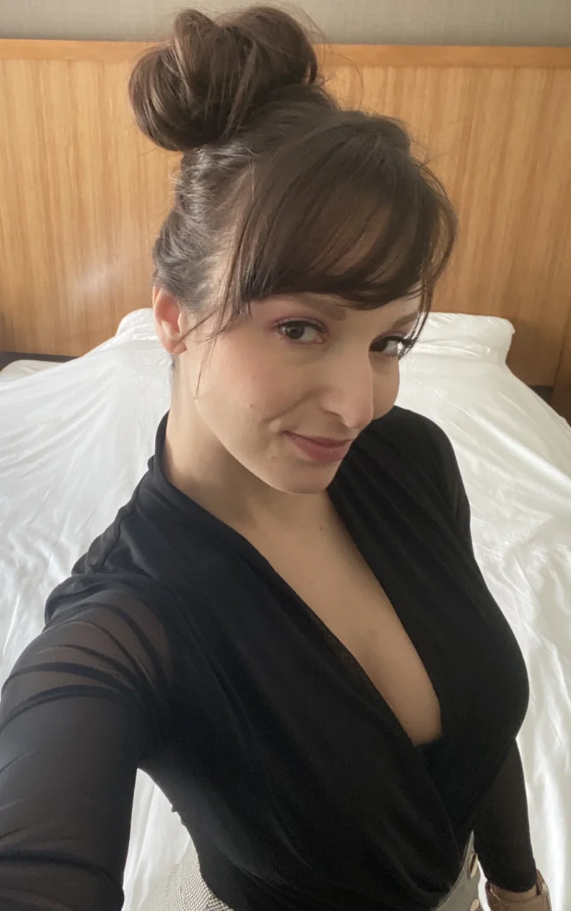 Naughty Lexi Luna in black sheer top, cleavage on display while posing on bed