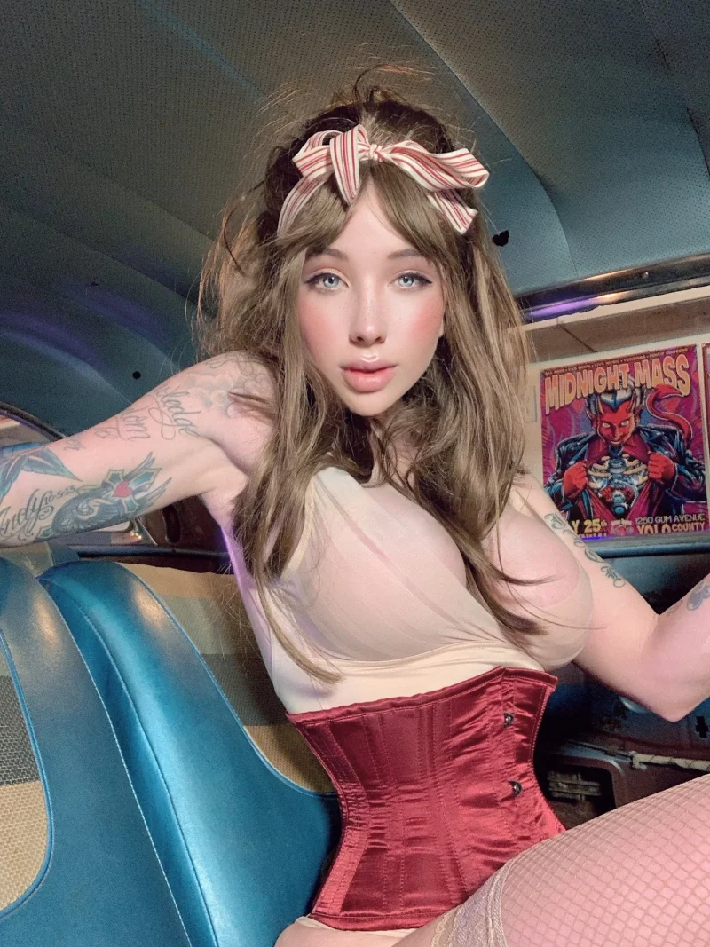 Sexy Coconut Kitty in red corset and fishnets poses topless in a vintage car