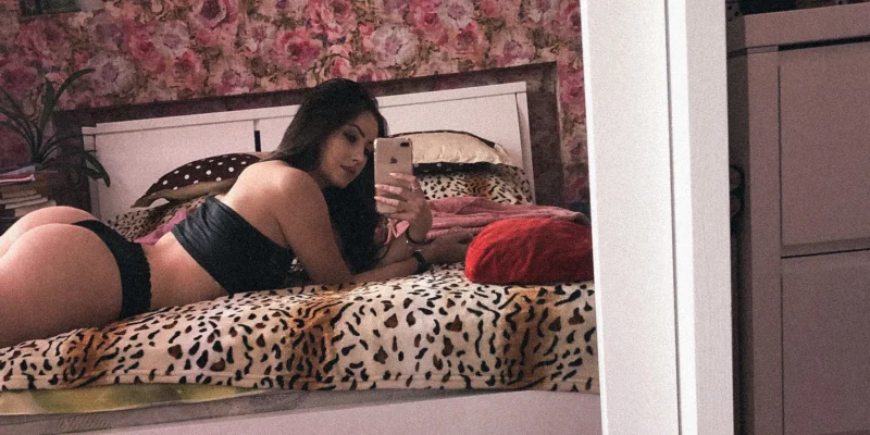 Sultry Anastasiia Mut in black lingerie takes a mirror selfie on leopard print bed