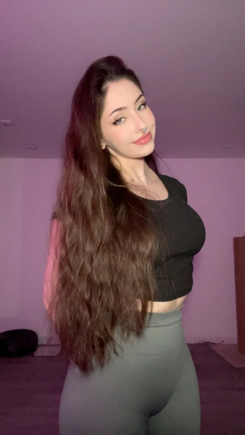 Flirty Anastasiia Mut in black crop top and grey leggings posing with long hair