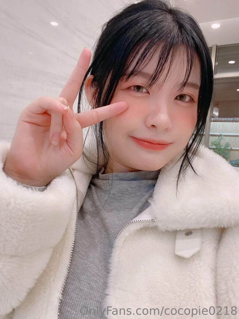 Sexy CocoPie in fluffy white jacket making peace sign with her fingers