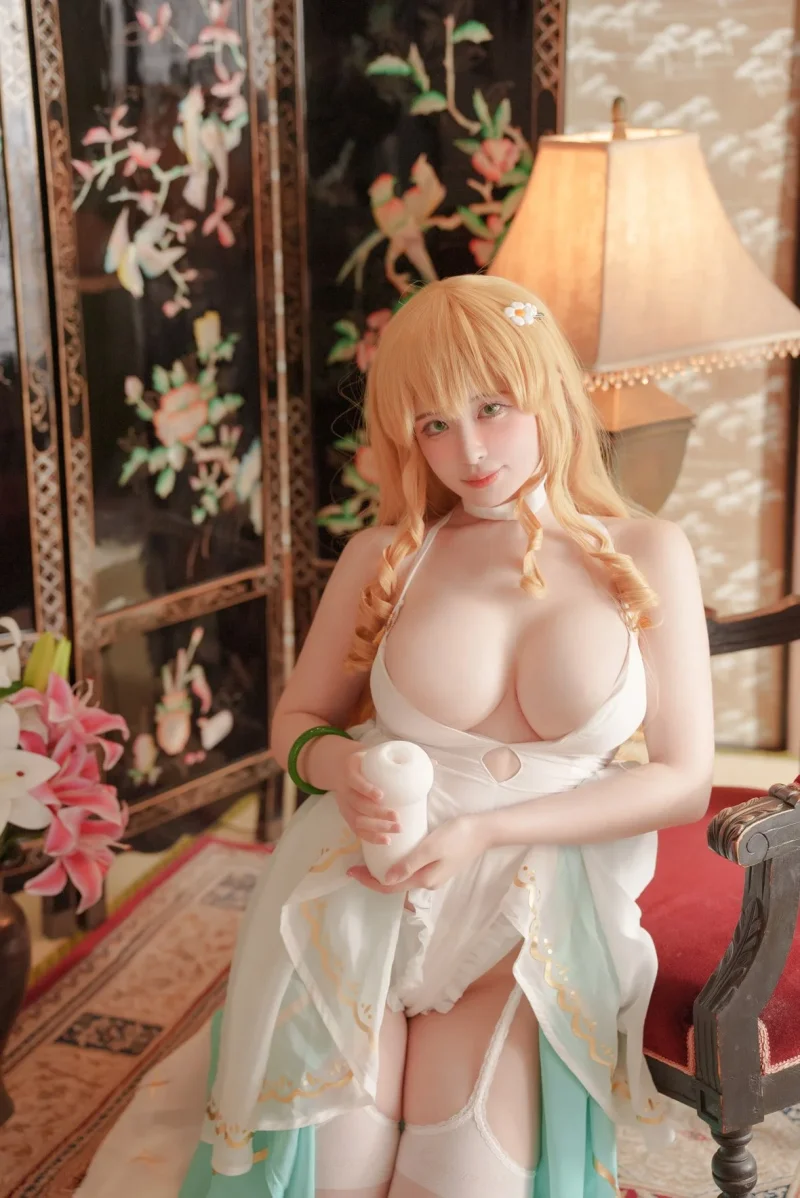 Flirty CocoPie in white lingerie holding a dildo while sitting on a red chair